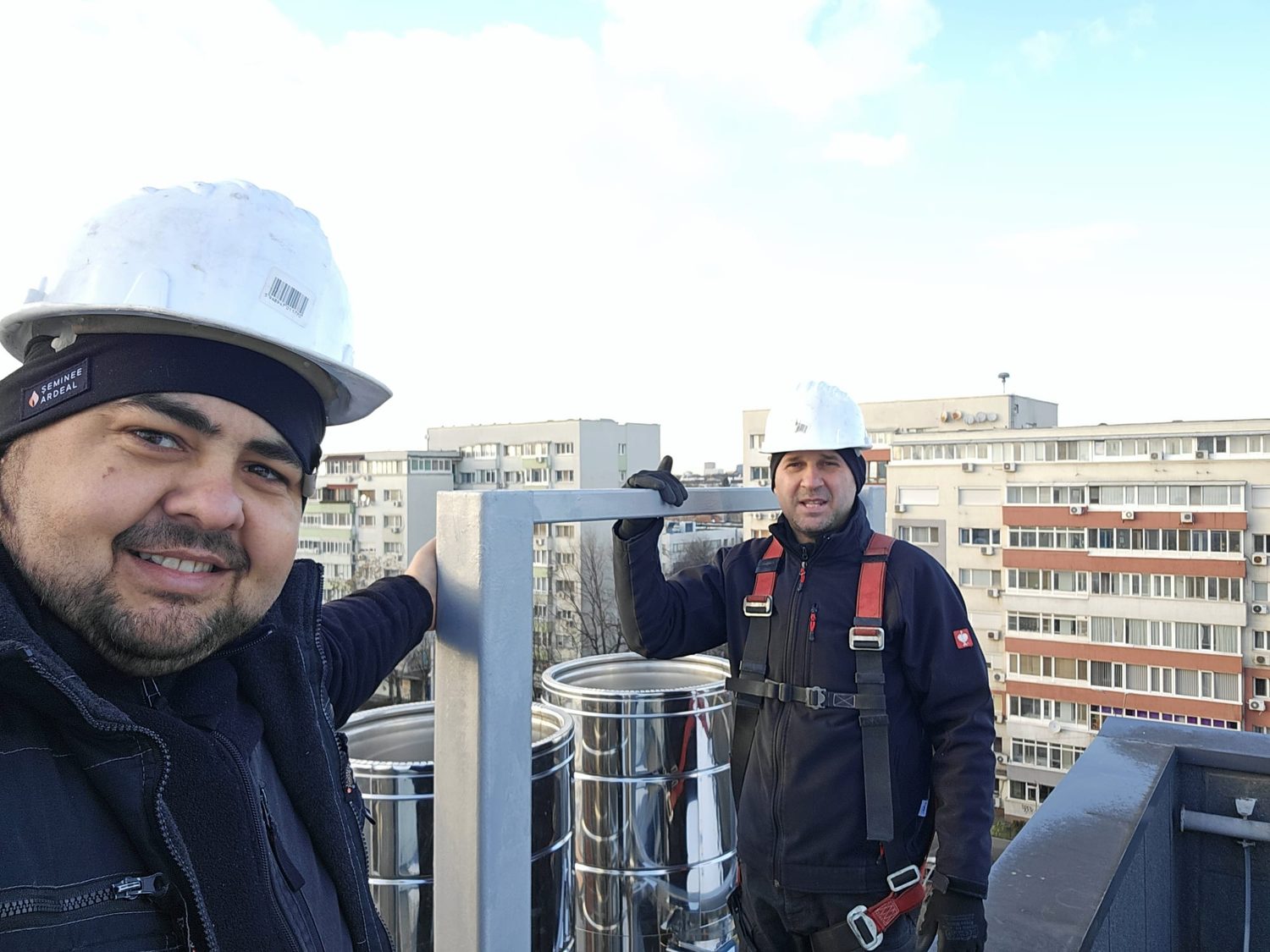 Doi tehnicieni Servicii Coșerit echipați pentru lucru la înălțime, pe terasa unei clădiri