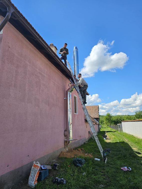Echipa montând coșul de fum pe acoperișul unei case