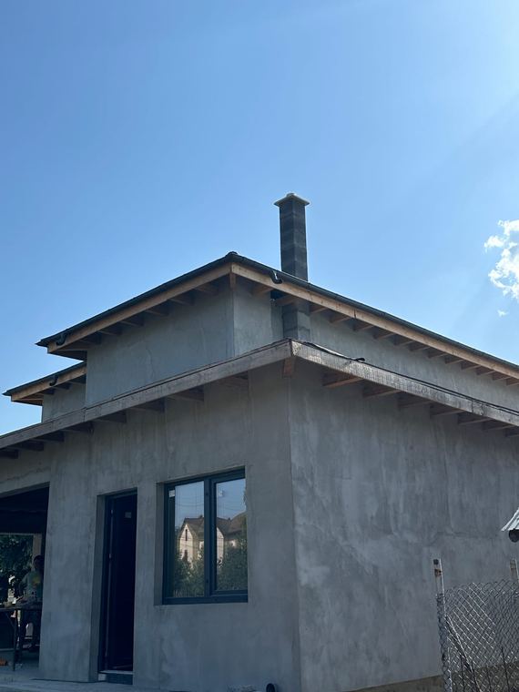 Coș de fum montat la o casă în construcție, cu tencuială la exterior
